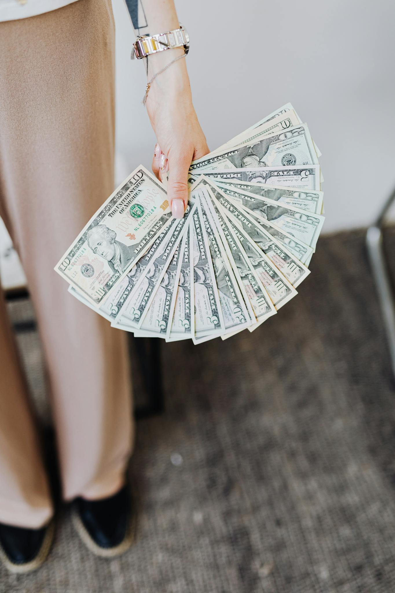 A person holds fanned US dollar bills, symbolizing wealth and finance.